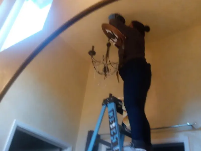 Electrician installing a chandelier in a Oaklyn residence